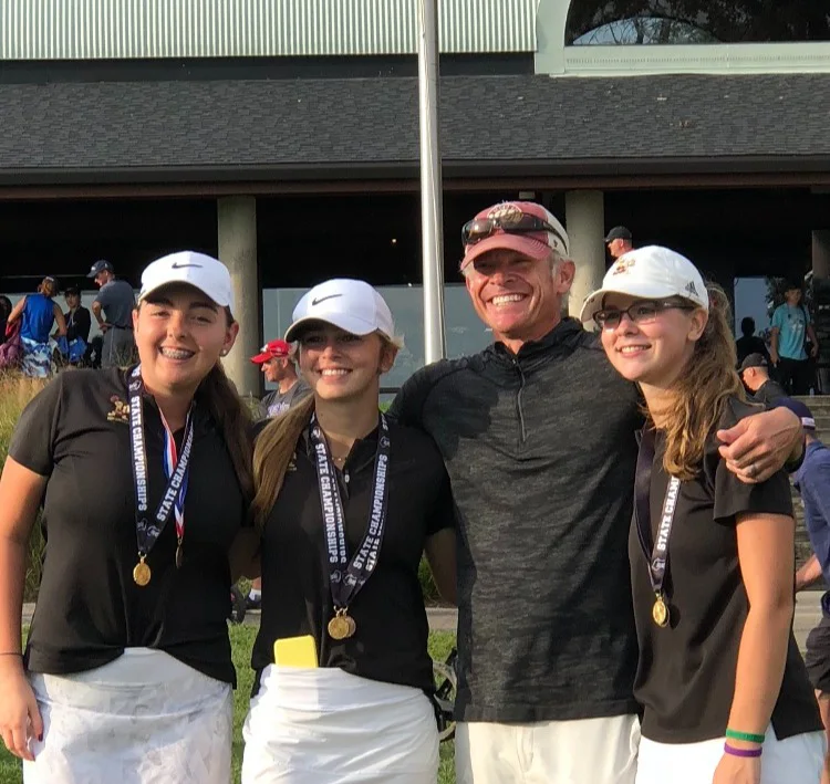 Derek Schnarr with three junior golfers wearing state championship medals outside a clubhouse