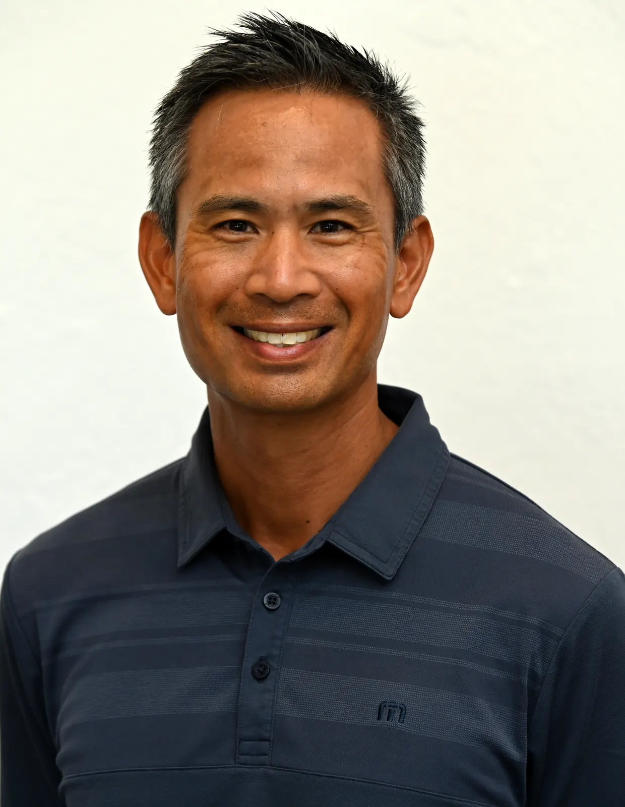 Portrait of Roger Pineda, golf professional and coach at Baylands Golf Links, smiling in a navy polo.